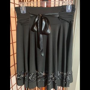 Black A-Line skirt with silk tie and flower pattern at the base. Size M